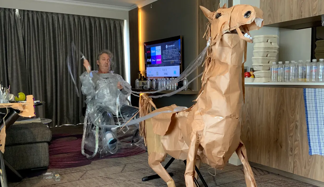 David Marriott berpose dengan kuda kertasnya Russell di kamar hotelnya di Brisbane, Australia, 6 April 2021. Saat berada dalam kamar hotel untuk karantina, direktur seni di iklan TV itu bosan dan mulai membuat pakaian koboi dari kantong kertas makanannya yang dikirimkan. (David Marriott via AP)