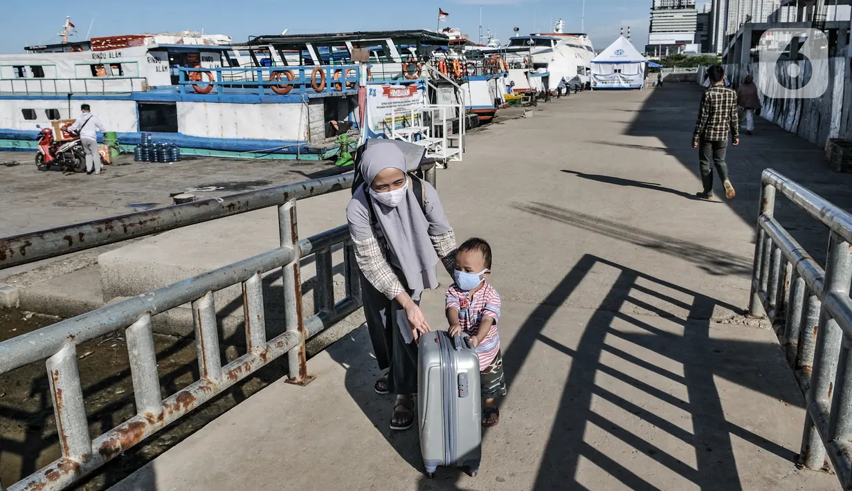 Seorang ibu dan anaknya mendorong koper bawaannya saat tiba di Dermaga Kali Adem, Muara Angke, Jakarta, Minggu (27/12/2020). Sebanyak 3.018 wisatawan berkunjung ke Kepulauan Seribu seperti Pulau Tidung, Pari, dan Pramuka untuk mengisi libur Natal (merdeka.com/Iqbal Nugroho)