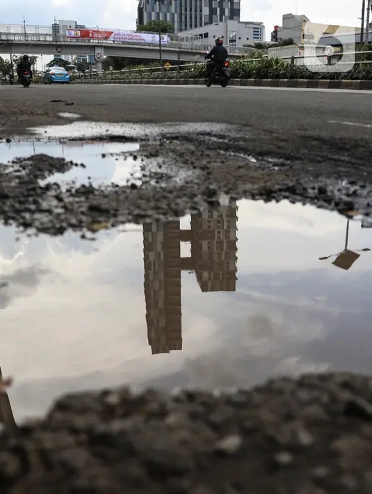 Sejumlah pengendara saat melintas dekat jalan yang berlubang di kawasan Gatot Subroto, Jakarta, Kamis (18/11/2021). Memasuki musim hujan yang turun hampir setiap hari membuat sejumlah ruas jalan rusak dan tergenang sehingga mengakibatkan jalan berlubang. (Liputan6.com/Johan Tallo)