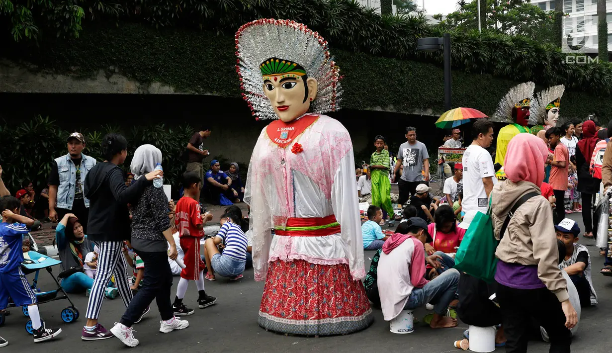 Boneka ondel-ondel berdiri diantara warga yang sedang beraktivitas di lokasi car free day, Jakarta, Minggu (21/5). (Liputan6.com/Immanuel Antonius)