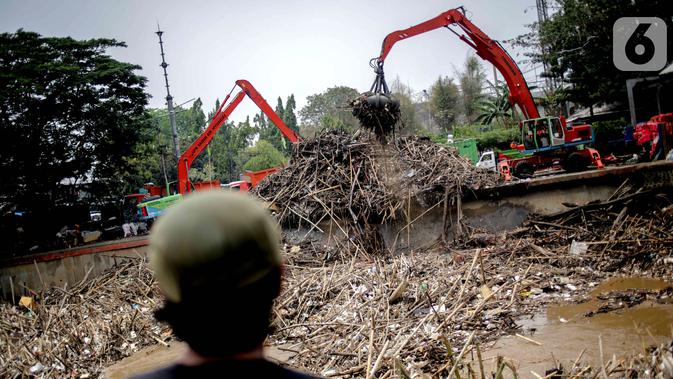 Petugas dibantu alat berat membersihkan sampah kayu dan bambu yang tersangkut di Pintu Air Manggarai, Jakarta, Rabu (9/10/2019). Sekitar 80 ton sampah diangkut menggunakan alat berat. (Liputan6.com/Faizal Fanani)