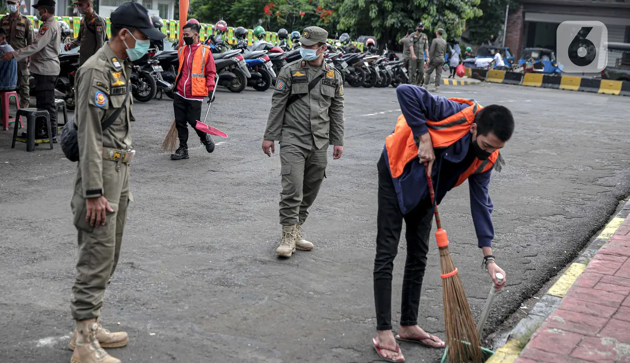 Petugas Satpol PP mengawasi warga yang menjalani sanksi sosial saat razia masker di kawasan Kota Tua, Jakarta, Kamis (24/2/2022). Pemerintah pusat kembali memperpanjang masa PPKM level 3 untuk wilayah Jakarta, Bogor, Depok, Tangerang dan Bekasi (Jabodetabek). (Liputan6.com/Faizal Fanani)