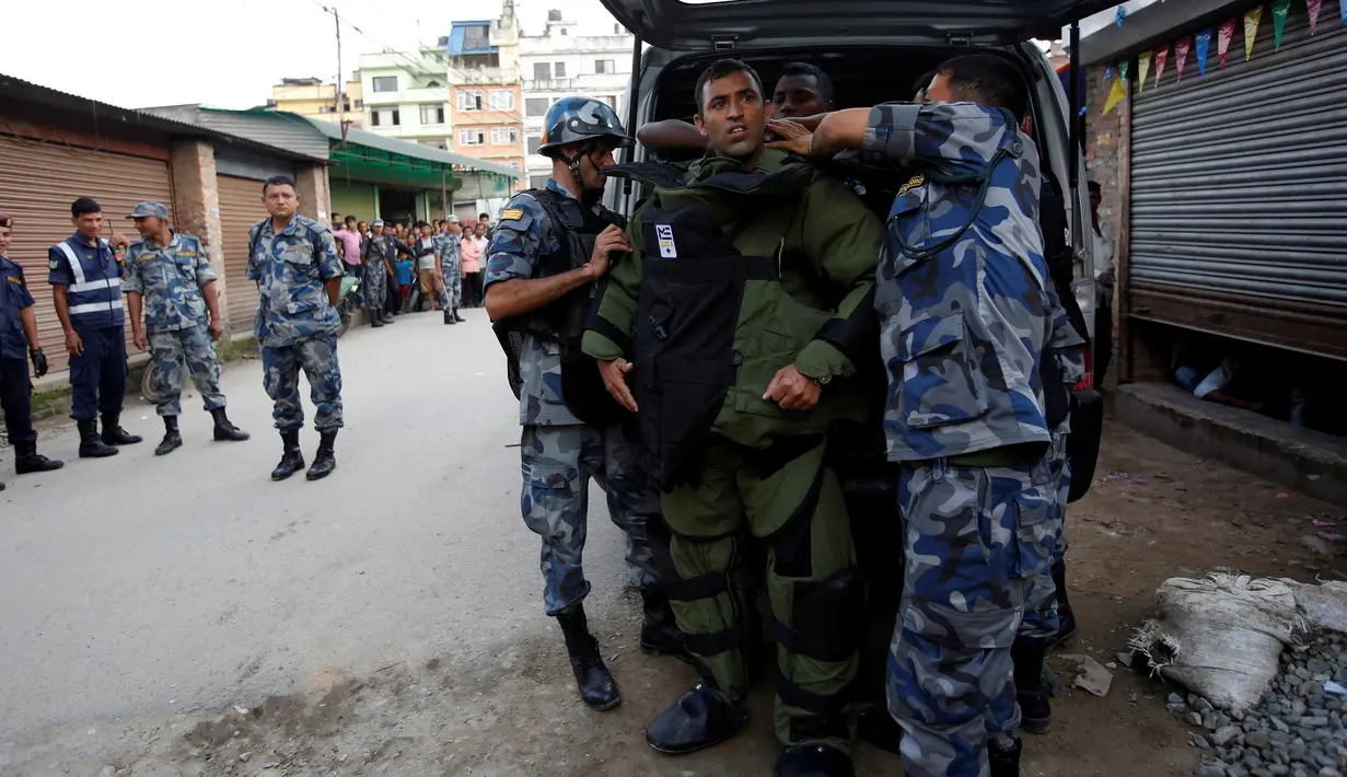 Anggota kepolisian bersiap menjinakkan bom yang ditemukan di sekitar sebuah sekolah di Kathmandu, Nepal, Selasa (20/9). Sebelumnya, bom Kecil telah meledak di luar dua sekolah di ibukota Nepal, Selasa pagi. (REUTERS/Navesh Chitrakar)