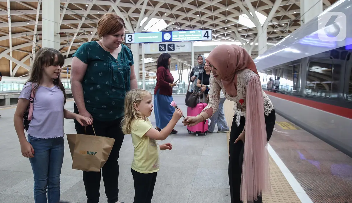 Petugas perempuan Kereta Cepat Whoosh mengenakan kebaya sambil membagikan bunga kepada calon penumpang di Stasiun Halim Whoosh, Jakarta, Senin (21/4/2025). (Liputan6.com/Angga Yuniar)
