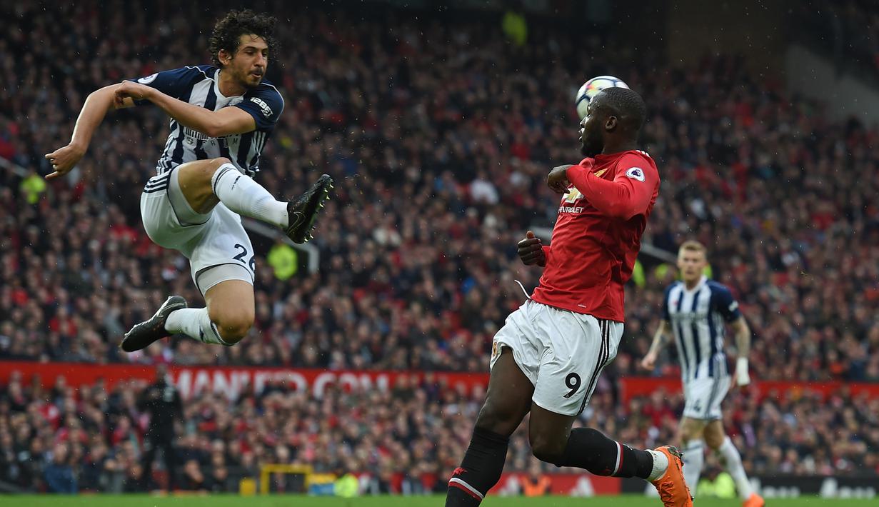 Pemain West Bromwich, Ahmed Hegazy (kiri) membuang bola dari kejaran pemain Manchester United, Romelu Lukaku pada lanjutan Premier League di Old Trafford, Manchester,(15/4/2018). Manchester United kalah 0-1. (AFP/Paul Ellis)