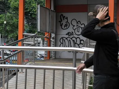 Warga melintas di Halte Transjakarta Koridor 13 yang terdapat coretan pada bagian pintu di Tendean, Jakarta, Senin (10/7). Aksi vandalisme ini merusak pemandangan Halte Transjakarta Koridor 13. (Liputan6.com/Yoppy Renato)