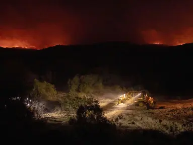 Alat berat dikerahkan untuk membuat sekat saat kebakaran hutan yang disebut Highland Fire membakar di Aguanga, California, Senin, 30 Oktober 2023. (AP Photo/Ethan Swope)