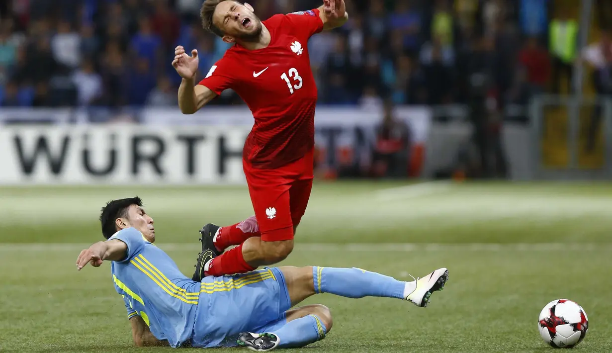 Pemain Kazakhstan, Abzal Beysebekov (kiri) menghalau bola dari kejaran pemain Polandia, Maciej Rybus pada laga kualifikasi piala dunia 2018 di Astana Arena Stadium, Astana, (5/9/2016) dini hari WIB. (REUTERS/Shamil Zhumatov)
