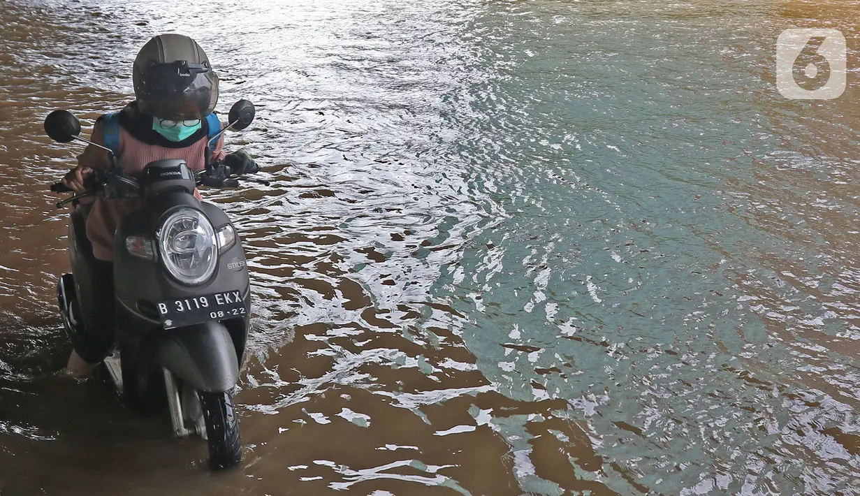 Warga mendorong sepeda motor setelah mogok akibat menerobos banjir di Jalan Ahmad Yani, Jakarta, Minggu (23/2/2020). Banjir yang terjadi dari dini hari tadi melumpuhkan akses jalan tersebut. (Liputan6.com/Herman Zakharia)