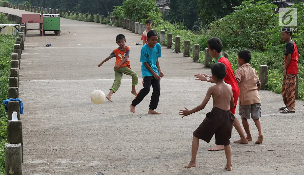 Anak-anak bermain sepak bola di jalur inspeksi Sungai Ciliwung di kawasan Rawajati, Jakarta, Rabu (23/1). Keterbatasan lahan tidak menyurutkan semangat mereka untuk bermain sepak bola meski di tempat seadanya. (Liputan6.com/Immanuel Antonius)