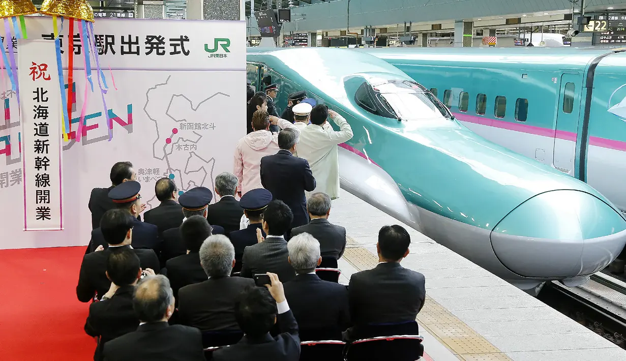 Warga saat menyambut dengan meriah kereta peluru Shinkansen tujuan Shin-hakodate-Hokuto di stasiun Tokyo, Sabtu (26/3). Dengan adanya jalur baru kereta supercepat ini perjalanan Tokyo-Hokkaido ditempuh hanya selama 4 jam 2 menit. (JIJI PRESS / AFP)