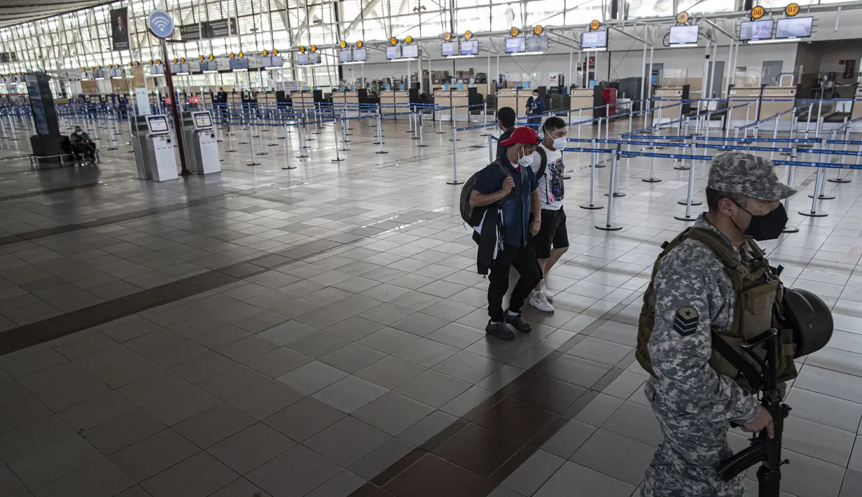 Seorang tentara dan beberapa penumpang berjalan di dalam bandara internasional Arturo Merino Benitez yang sepi pada hari pertama pemerintah menutup perbatasan di Santiago, Chile, Senin (5/4/2021). Kasus COVID-19 telah melonjak di Chile meskipun ada upaya vaksinasi. (AP Photo/Esteban Felix)