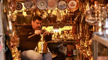 Pedagang barang antik Saadoun Mansouri bekerja di tokonya di Baghdad, Irak, Rabu (20/3). (AP Photo/Hadi Mizan)