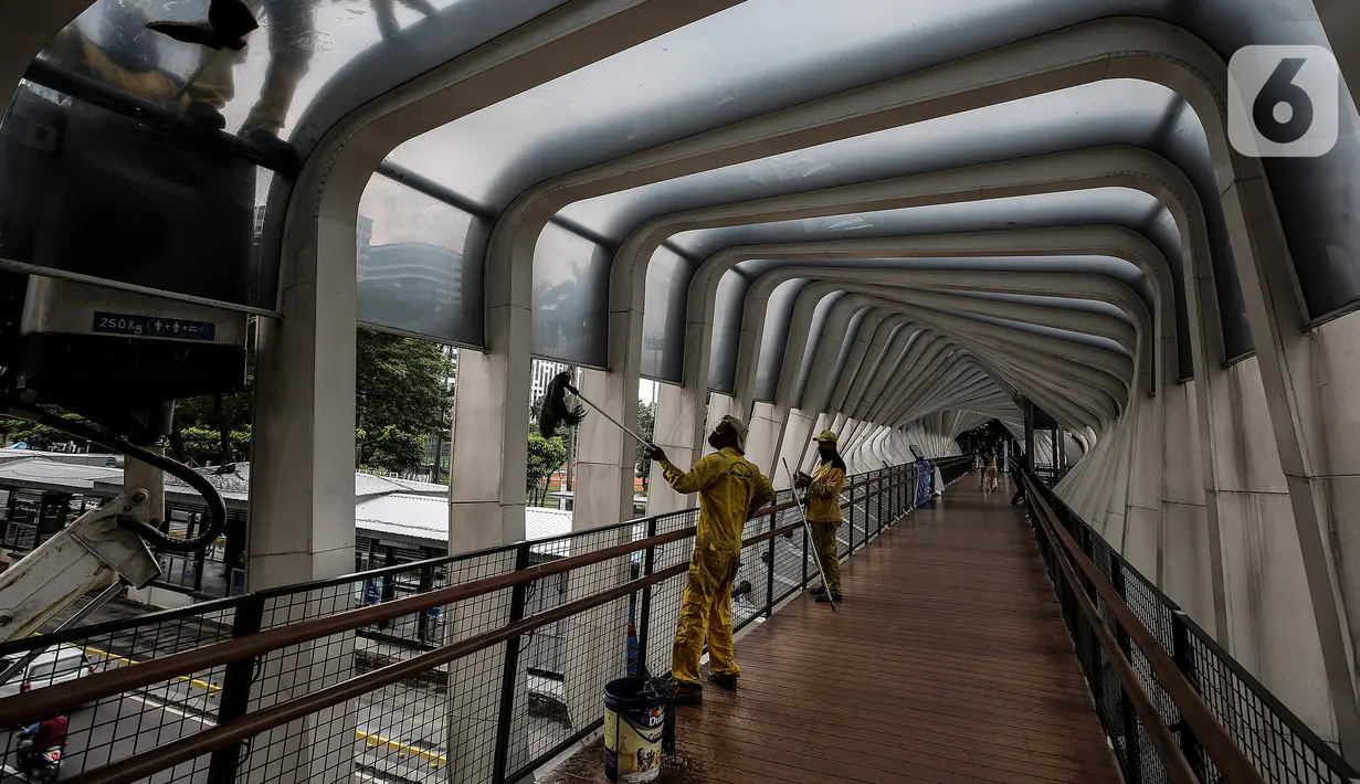 Pasukan kuning dari Dinas Bina Marga DKI Jakarta melakukan perawatan Jembatan Penyeberangan Orang (JPO) di Kawasan Sudirman, Senin (29/3/2021). Kegiatan tersebut dilakukan agar bersih terhidar dari debu serta para pemakai jembatan itu merasa aman dan nyaman. (Liputan6.com/Johan Tallo)