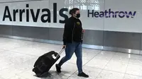 Potret yang diambil pada 10 Juli 2020 ini, menampilkan penumpang mengenakan masker akibat pandemi COVID-19, baru tiba di Bandara Heathrow, London barat. (DANIEL LEAL-OLIVAS / AFP)