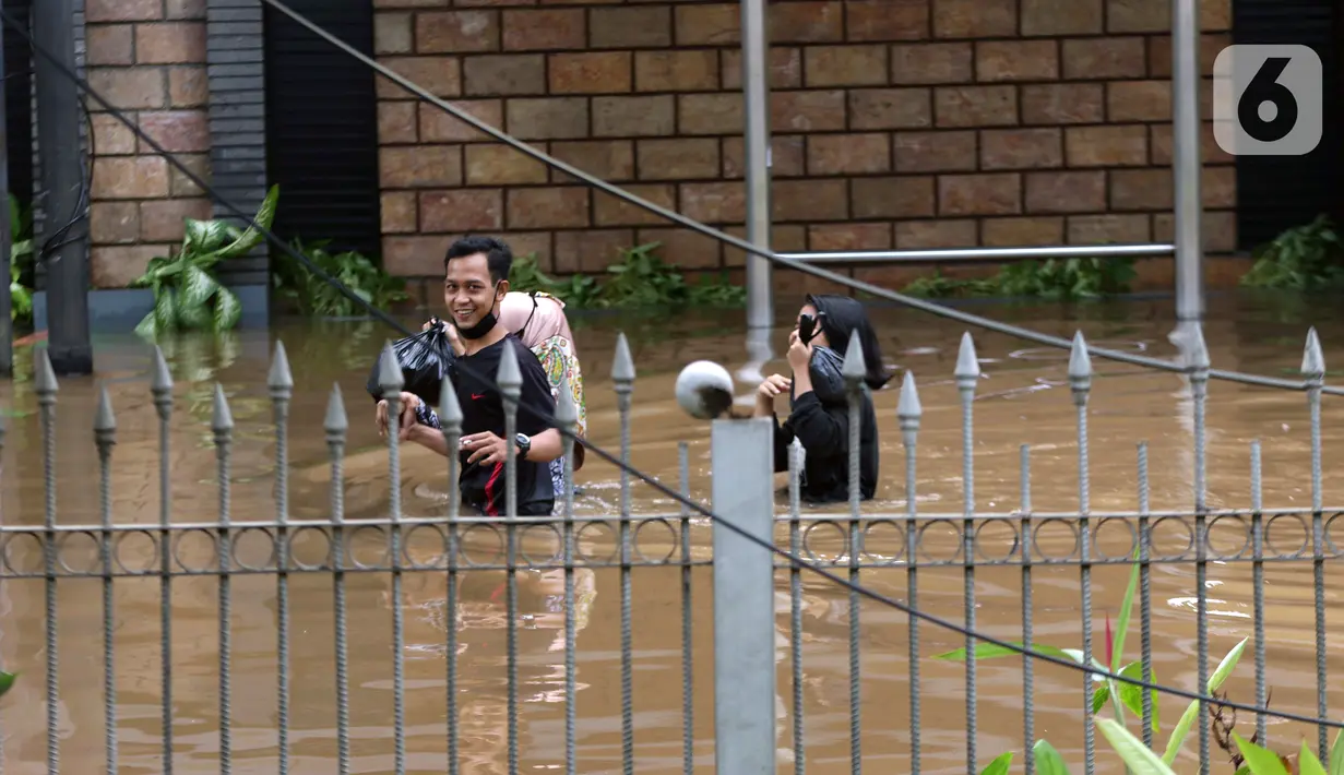 Warga berjalan menyusuri banjir yang menggenangi sebagian ruas Jalan Warung Buncit Raya, Jakarta, Sabtu (20/2/2021). Hujan yang mengguyur Jakarta sejak Jumat (19/2) membuat arus lalu lintas sejumlah jalan di Jakarta lumpuh akibat terendam banjir. (Liputan6.com/Helmi Fithriansyah)