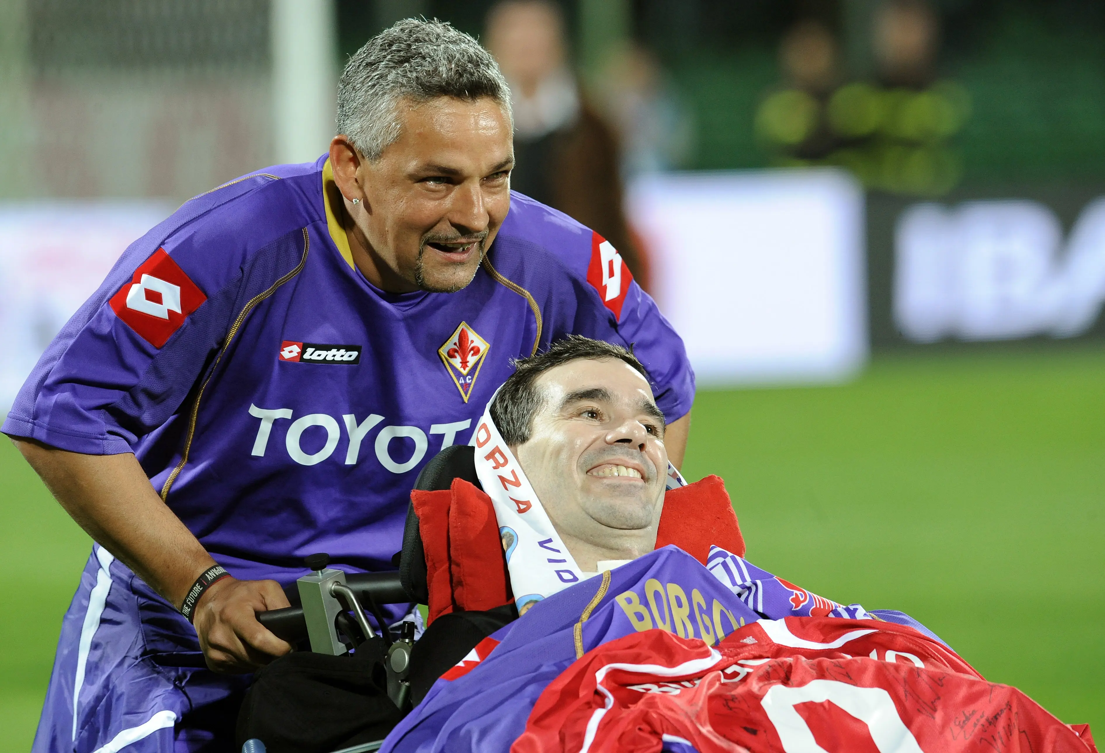Roberto Baggio mendorong kursi roda mantan rekan setimnya di Fiorentina, Stefano Borgonovo, yang menderita Amyotrophic Lateral Sclerosis (ALS) pada 8 Oktober 2008. (FILIPPO MONTEFORTE / AFP)