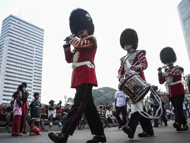 Scotts Guard alias penjaga Buckingham Palace melakukan aksi mengelilingi di Bundaran HI, Jakarta, Minggu (5/6). Aksi Scotts Guard yang didatangkan dari Inggris ini dalam rangka hari ulang tahun Ratu Elizabeth II yang ke-90. (Liputan6.com/Faizal Fanani)