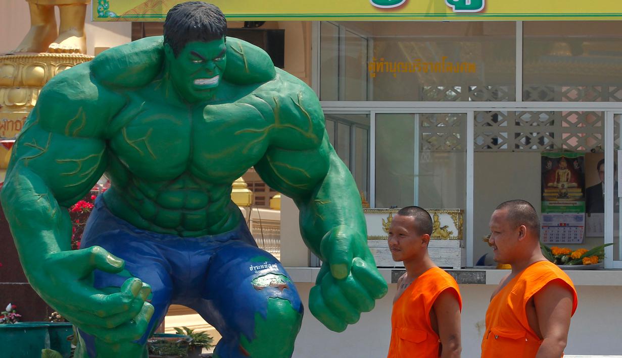 Dua orang biksu melintas di dekat patung "Hulk" di kuil Tamru di Samut Prakan, Thailand (3/3). Pihak Candi mengatakan telah menyiapkan patung-patung karakter komik Marvel untuk menarik pengunjung. (REUTERS/Chaiwat Subprasom)