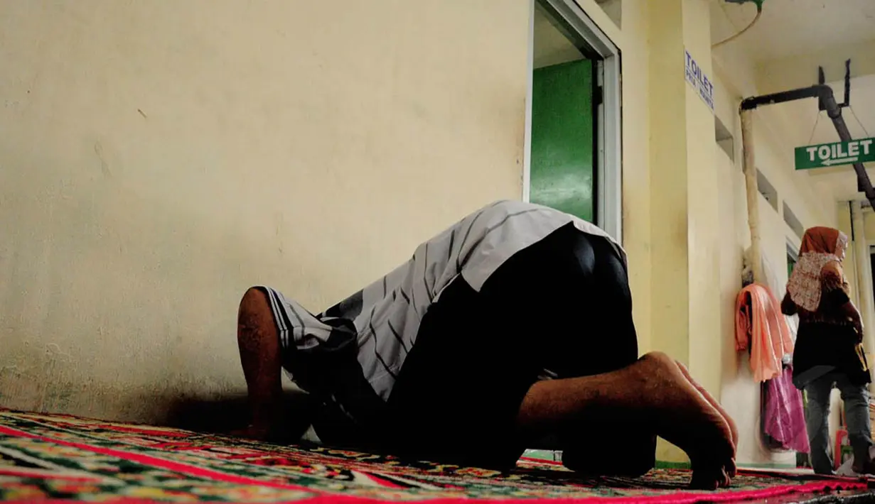 Seorang pedagang laki-laki tampak sholat persis di depan toilet umum di Pasar Blok G, Tanah Abang, Jakarta, (8/7/2014) (Liputan6.com/ Faizal Fanani)