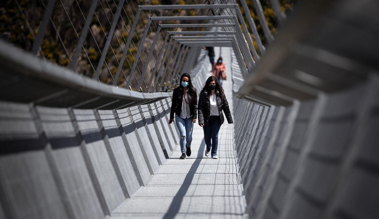 Orang-orang berjalan melewati Jembatan 516 Arouca di Arouca, Portugal (29/4/2021). Jembatan 516 Arouca merupakan jembatan gantung terpanjang di dunia yang membentang sejauh 516 meter di ketinggian 175 meter. (AFP/Carlos Costa)