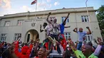 Warga Zimbabwe bergembira setelah kabar Presiden Robert Mugabe mengundurkan diri di luar gedung parlemen, pusat kota Harare, Selasa (21/11). Surat pengunduran diri Robert Mugabe itu mengakhiri masa pemerintahannya selama 37 tahun. (AP/Ben Curtis)