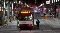 Orang-orang menyeberang jalan selama aturan jam malam di Melbourne, pada Selasa (17/8/2021). Kota terbesar kedua di Australia itu memberlakukan pembatasan tinggal di rumah pada pukul 9 malam hingga 5 pagi untuK meredam lonjakan Covid-19 varian Delta. (William WEST/AFP)