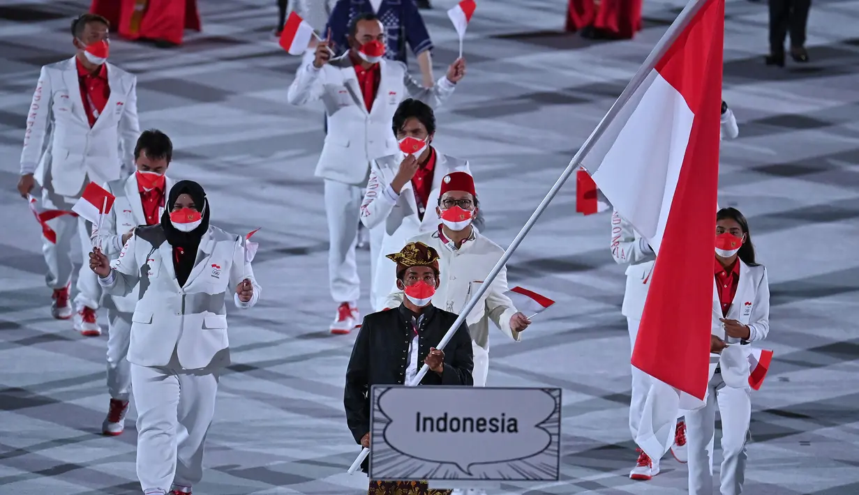Kontingen Indonesia mengikuti defile dalam pembukaan Olimpiade Tokyo 2020, di Stadion Nasional Jepang, Tokyo, Jumat malam (23/7/2021). Upacara pembukaan Olimpiade Tokyo yang berlangsung dalam era pandemi, dan digelar tanpa penonton. (Ben STANSALL/AFP)