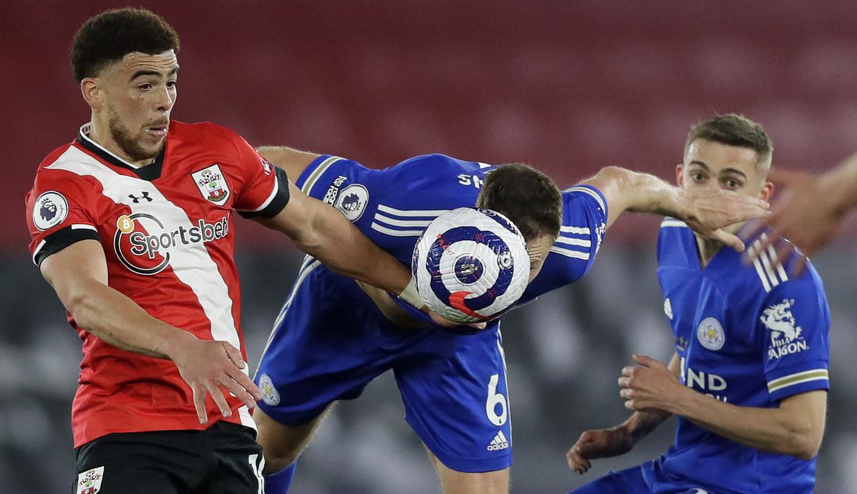 Bek Leicester City, Jonny Evans (tengah) berebut bola dengan gelandang Southampton, Che Adams (kiri) dalam laga lanjutan Liga Inggris 2020/2021 pekan ke-34 di St Mary's Stadium, Southampton, Jumat (30/4/2021). Leicester bermain imbang 1-1 dengan Southampton. (AFP/Kirsty Wigglesworth/Pool)