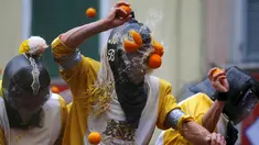 Seorang peserta dilempari jeruk saat perang-perangan selama karnaval di kota Ivrea, Italia, Minggu (7/2). Peserta yang dibagi menjadi dua tim ini saling melempar jeruk menggunakan kostum dan aksesoris lengkap. (REUTERS/Stefano Rellandini)