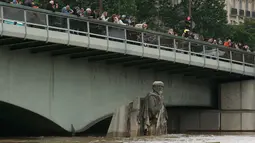 Warga melihat patung Zouave yang terendam banjir dari Sungai Seine setelah hampir setiap hari hujan lebat di Paris, Prancis, (3/6). Banjir yang merendam sebagian wilayah Prancis Sejauh ini sudah dua orang tewas. (REUTERS/Pascal Rossignol)