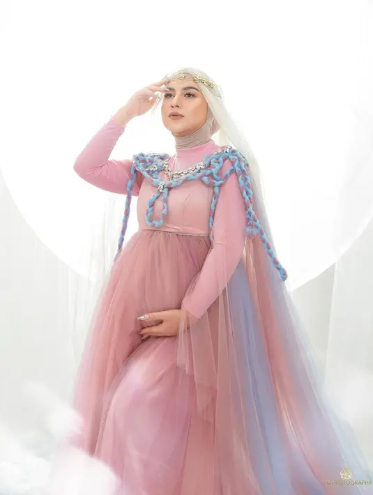 Dalam foto maternity lainnya, ia juga memakai dress pink dengan aksen rok tutu bergradasi biru. Terdapat detail tali kepang yang menambah cantik penampilannya. 
(Foto: Instagram @_irishbella_)