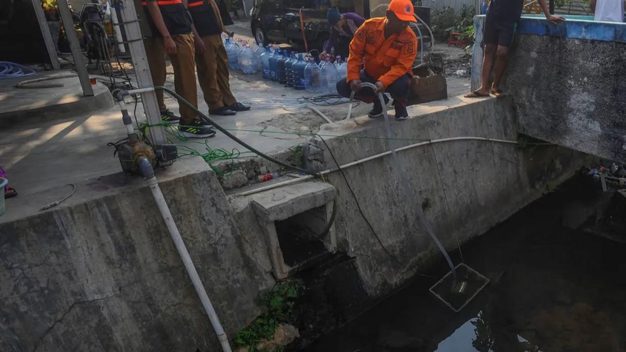Petugas BPBD menggunakan selang saat mengambil sumber air dari sungai di lingkungan rumah warga di kawasan Kranggan, Tangerang Selatan.