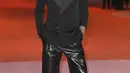 Lenny Kravitz tampil mengenakan oversized tuxedo peacoat dalam wol, wide-leg pants dalam lambskin, blaze sunglasses, dan zipped boots dari kulit yang lembut. Penampilannya ini berasal dari Saint Laurent. [Foto: Document/Saint Laurent]