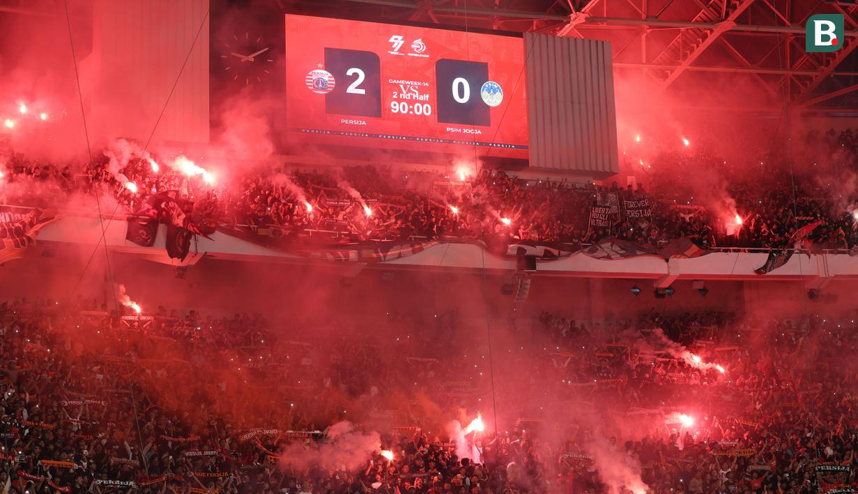 The Jakmania menyalakan Flare saat merayakan kemenangan Persija Jakarta atas PSIM Yogyakarta pada laga pekan ke-14 BRI Super League 2025/2026 di Stadion Utama Gelora Bung Karno, Jakarta, Jumat (28/11/2025) malam. (Bola.com/M Iqbal Ichsan)