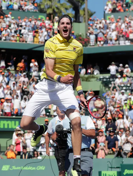 Petenis AS, John Isner melompat merayakan kemenangan atas petenis Jerman Zverev di final Miami Terbuka 2018, Minggu (1/4). Kemenangan ini akan membuat Isner menjadi petenis AS dengan peringkat tertinggi, urutan kesembilan. (AP/Lynne Sladky)