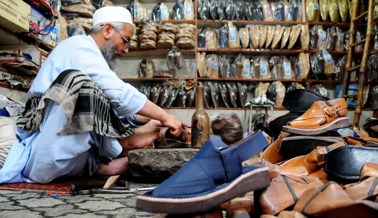 Seorang pembuat sepatu asal Pakistan membuat sepatu tradisional yang dikenal sebagai "chapli" di kalangan penduduk lokal untuk menyambut Hari Raya Idul Fitri di Peshawar, Pakistan barat laut, pada 19 Mei 2020. (Xinhua/Saeed Ahmad)