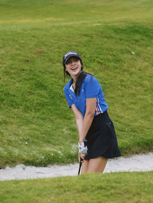 Anya Geraldine tersenyum saat bermain golf . Pada foto tersebut ia mengenakan baju berwarna biru dan rok pendek berwarna hitam. Pakaian yang ia kenakan berhasil membuat pesona seksinya semakin memancar. (Instagram/anyageraldine)