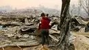 Juan Vega memeluk putrinya sambil meratapi rumah mereka yang hangus dilalap api di Santa Olga, Chile, (26/1). Sebanyak 6.000 warga berhasil menyelamatkan diri dari kebakaran hebat tersebut. (AP Photo/Esteban Felix)