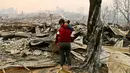 Juan Vega memeluk putrinya sambil meratapi rumah mereka yang hangus dilalap api di Santa Olga, Chile, (26/1). Sebanyak 6.000 warga berhasil menyelamatkan diri dari kebakaran hebat tersebut. (AP Photo/Esteban Felix)