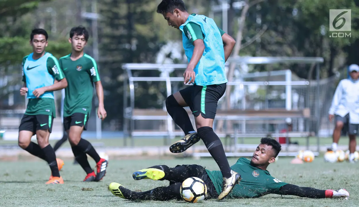 Kiper Timnas Indonesia U-19, Aqil Savik (bawah) berusaha menahan bola saat latihan di Lapangan B Kompleks GBK, Jakarta, Selasa (18/9). Latihan ini persiapan  PSSI Anniversary Cup U-19 dan Piala AFC U19. (Liputan6.com/Helmi Fithriansyah)