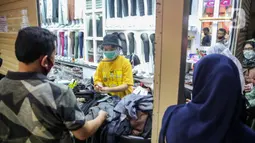 Pedagang melayani pembeli pakaian di salah satu kios Pasar Tanah Abang Blok A, Jakarta, Senin (15/6/2020). Setelah hampir tiga bulan ditutup, kawasan Pasar Tanah Abang kembali beroperasi pada Senin (15/6) diikuti dengan penerapan protokol kesehatan pencegahan Covid-19. (Liputan6.com/Faizal Fanani)