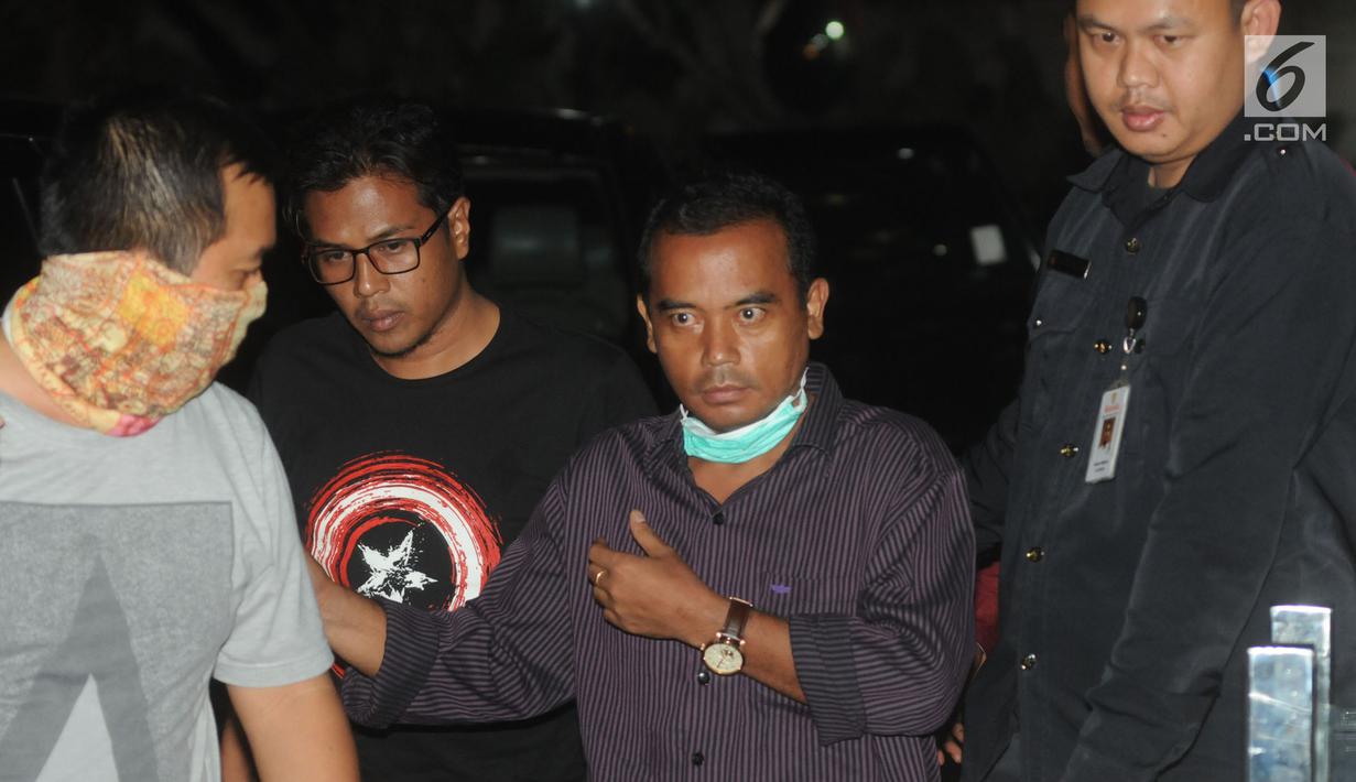 Bupati Purbalingga Tasdi (kemeja ungu) dikawal oleh petugas KPK menuju ruang pemeriksaan, Jakarta, Selasa (5/6). Tasdi dibawa tim penyidik KPK ke Jakarta dengan menggunakan kereta api ini sempat memperlihatkan salam metal. (Merdeka.com/Dwi Narwoko)