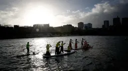 Peserta mengambil bagian dalam Nautic Paddle Race menyeberangi sungai Seine di Paris, Minggu (9/12). Sekitar 800 orang mengikuti lomba dayung sambil berdiri terbesar di dunia sejauh 11 km menyeberangi sungai Seine. (AP /Christophe Ena)