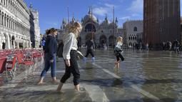 Orang-orang berjalan di St. Mark's Square yang terendam banjir di Venesia, Italia, Jumat (5/11/2021). Setelah Venesia mengalami banjir terparah kedua dalam sejarahnya pada November 2019, kota itu dibanjiri empat kali pasang luar biasa dalam waktu enam minggu. (AP Photo/Luigi Costantini)