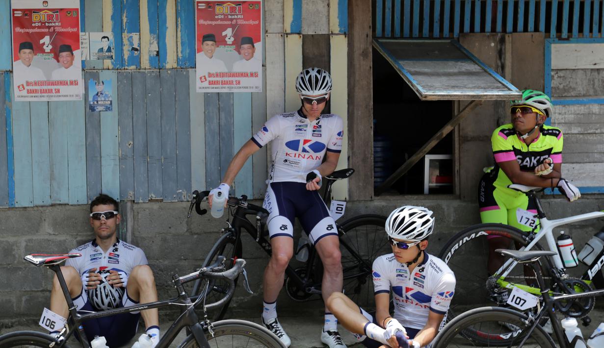 Para pebalap sepeda beristirahat sebelum melakukan start ulang di Titik Nol Kilometer Painan, Kabupaten Pesisir Selatan, Sumatra Barat saat Etape 1 Tour de Singkarak, Sabtu (3/10/2015). (Bola.com/Arief Bagus)