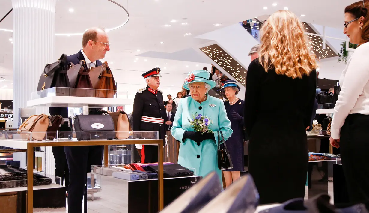 Ratu Elizabeth II melihat-lihat etalase tas di department store Fenwick saat mengunjungi pusat perbelanjaan Lexicon di Bracknell, London, Jumat (19/10). Saat berbelanja, area tersebut dikosongkan hanya untuk Ratu Elizabeth. (HENRY NICHOLLS/ POOL/AFP)