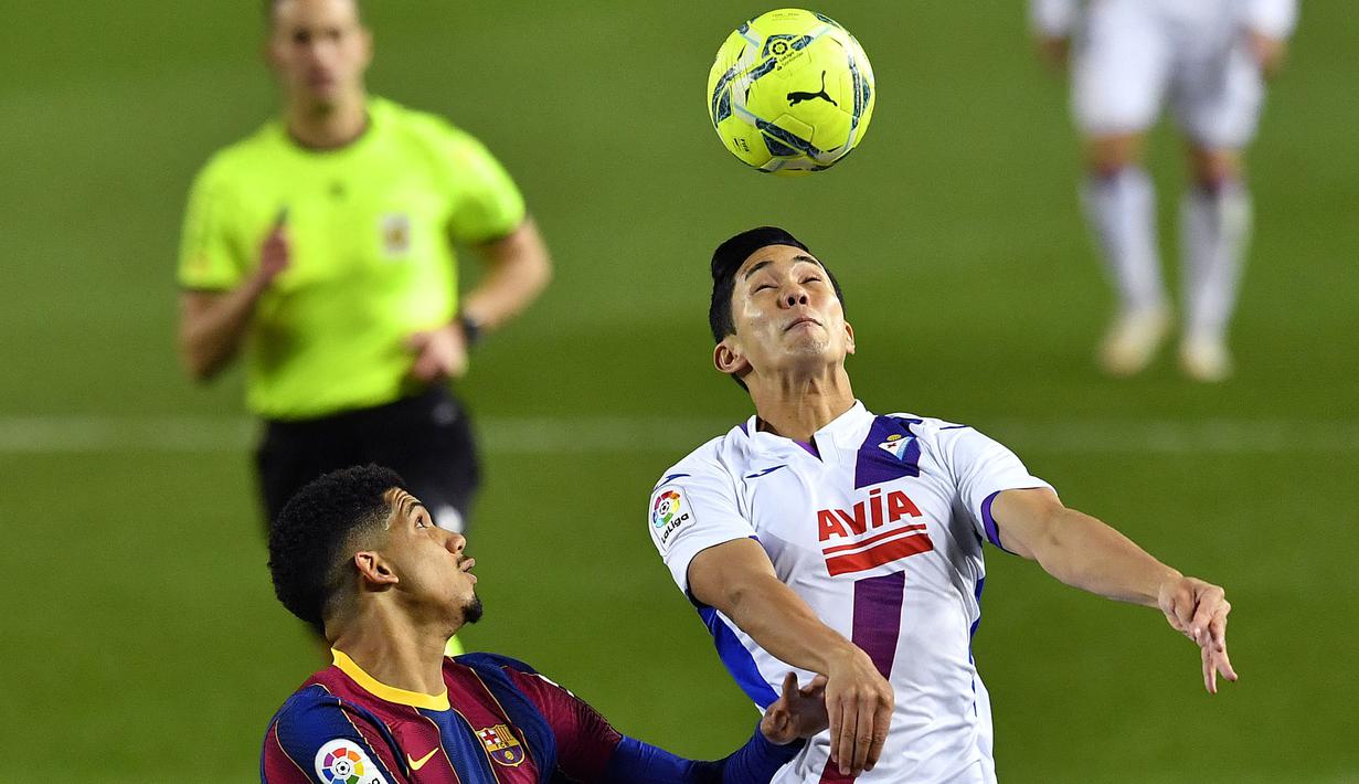 Pemain Eibar, Yoshinori Muto (kanan) berebut bola dengan pemain Barcelona, Ronald Araujo pada laga lanjutan Liga Spanyol 2020/2021 di Stadion Camp Nou, Barcelona, 29 Desember 2020. (AFP/Pau Barrena)
