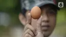 Pedagang menunjukkan telur saat berjualan di pinggir jalan kasawan Perumahan Nusa Indah, Tangerang Selatan, Banten, Jumat (22/5/2020). Jelang Lebaran, harga telur eceran terpantau masih normal. (merdeka.com/Dwi Narwoko)