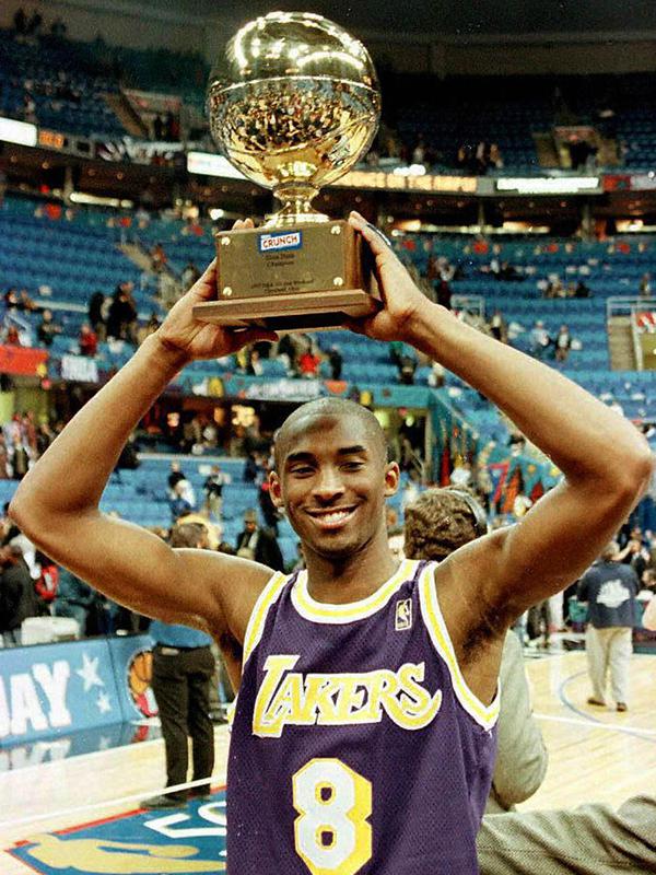 Pemain Los Angeles Lakers, Kobe Bryant mengangkat piala setelah memenangkan kontes NBA Slam Dunk di Gund Arena di Cleveland, Ohio pada 8 Februari 1997. Bryant meninggal bersama putrinya yang berusia 13 tahun Gianna dalam kecelakaan helikopter di Calabasas. (AFP/Jeff Haynes)